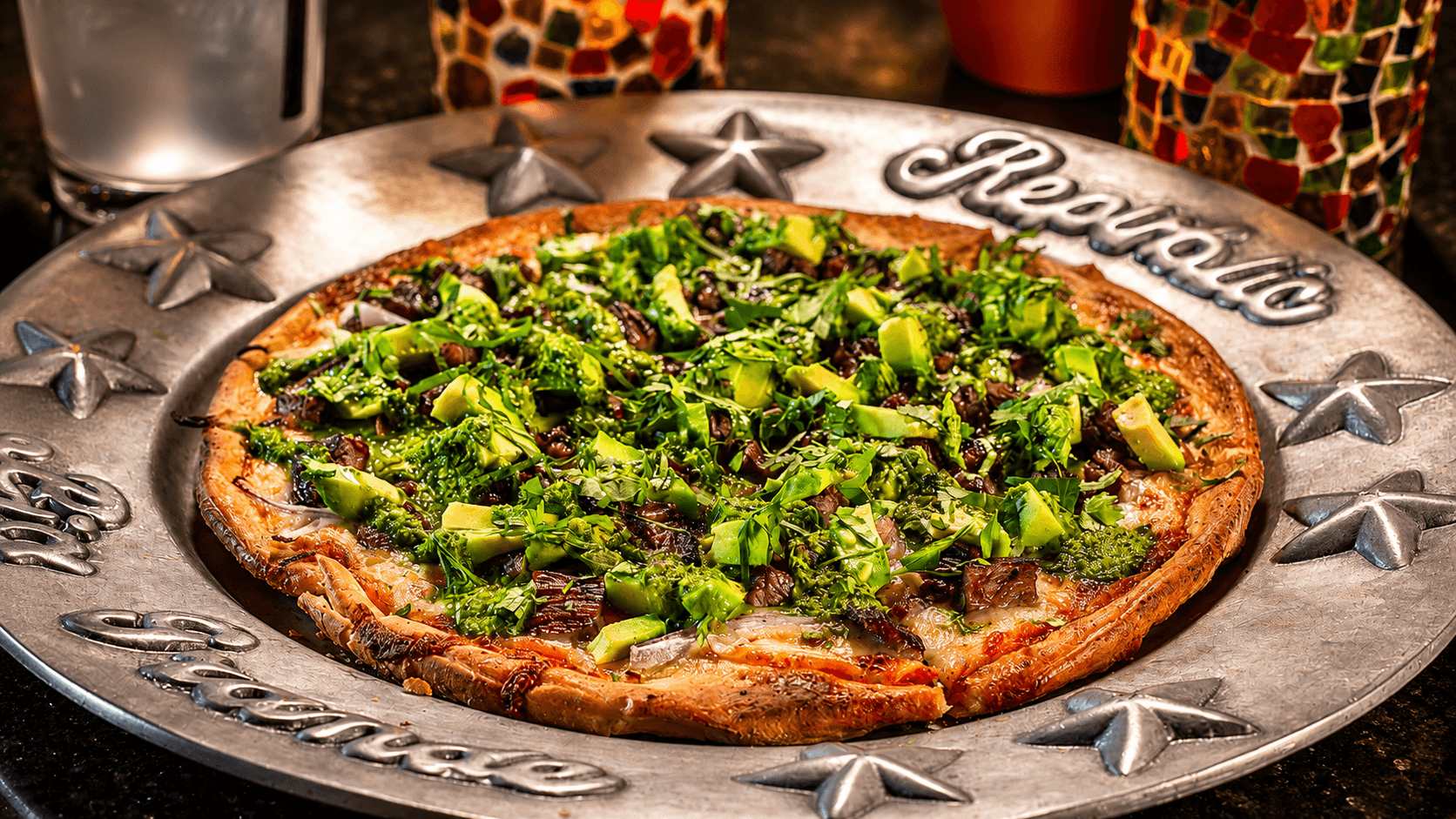 Brick-oven pizza with avocado, arugula, and fresh greens on the branded Republic pewter platter